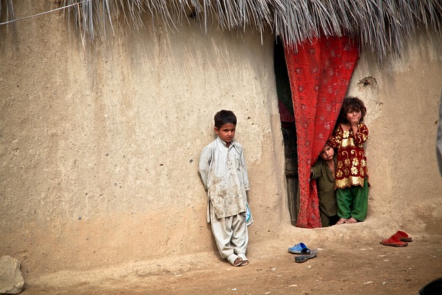 Children playing outside a mud house.