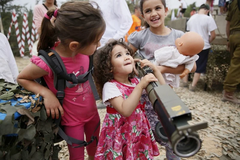 Israeli children being made to hold rocket launches and dangerous weapons, to militarise them against Arabs.